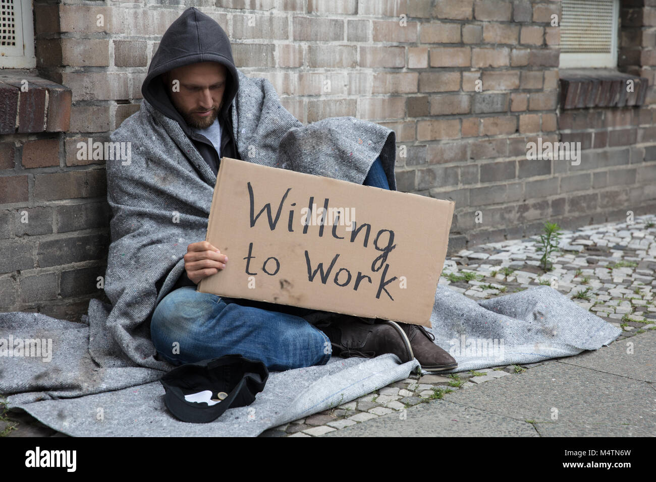 Obdachloser in der Motorhaube sitzen auf der Straße halten Karton mit Text bereit zu arbeiten Stockfoto