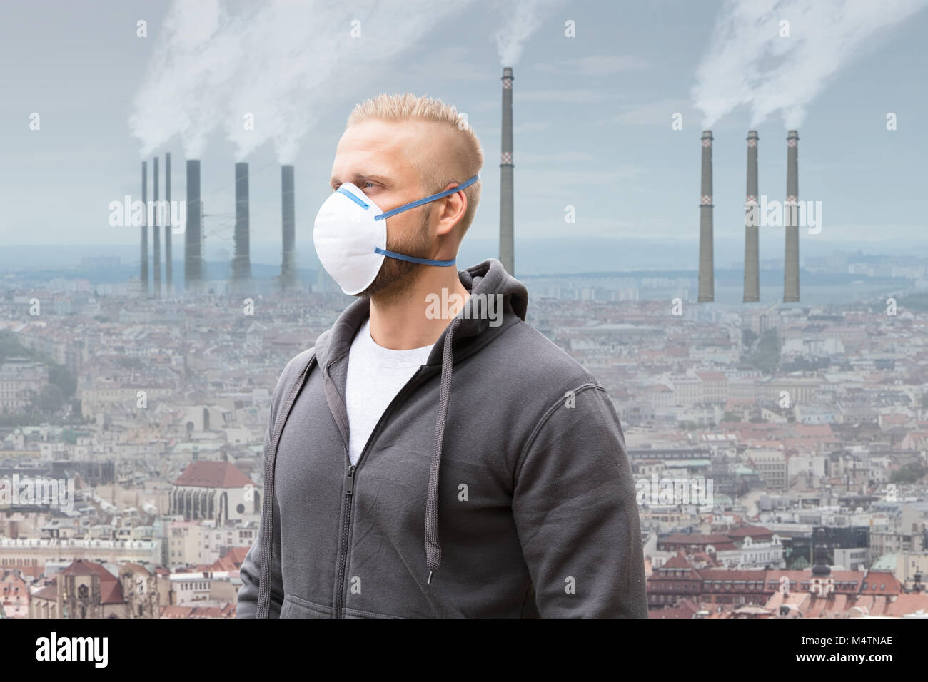 Ein Mann, der Verschmutzung Maske gegen Rauch ausstoßen von Fabrikschornsteinen Stockfoto