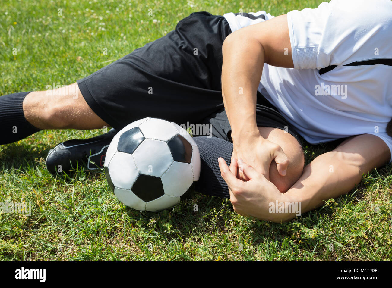 Nahaufnahme der männlichen Fußball-Spieler Leiden Knieverletzung liegen auf Feld Stockfoto