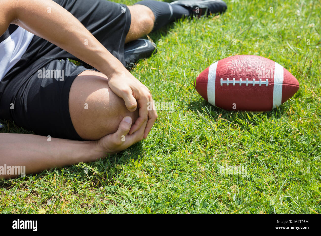 Nahaufnahme der männlichen Rugbyspieler Leiden Knieverletzung liegen auf Feld Stockfoto