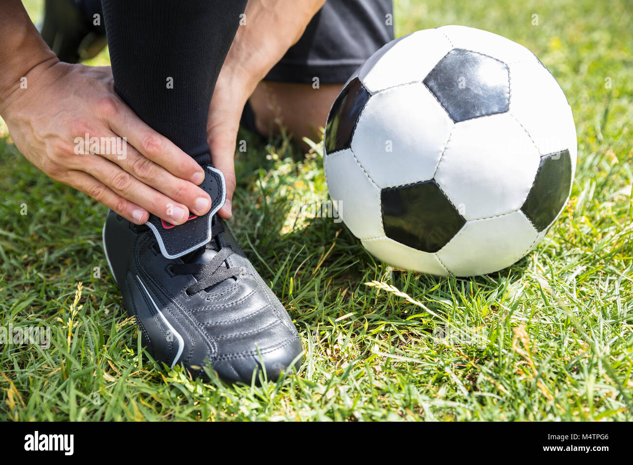 Nahaufnahme der männlichen Fußball-Spieler Leiden Knöchelverletzung auf Feld Stockfoto