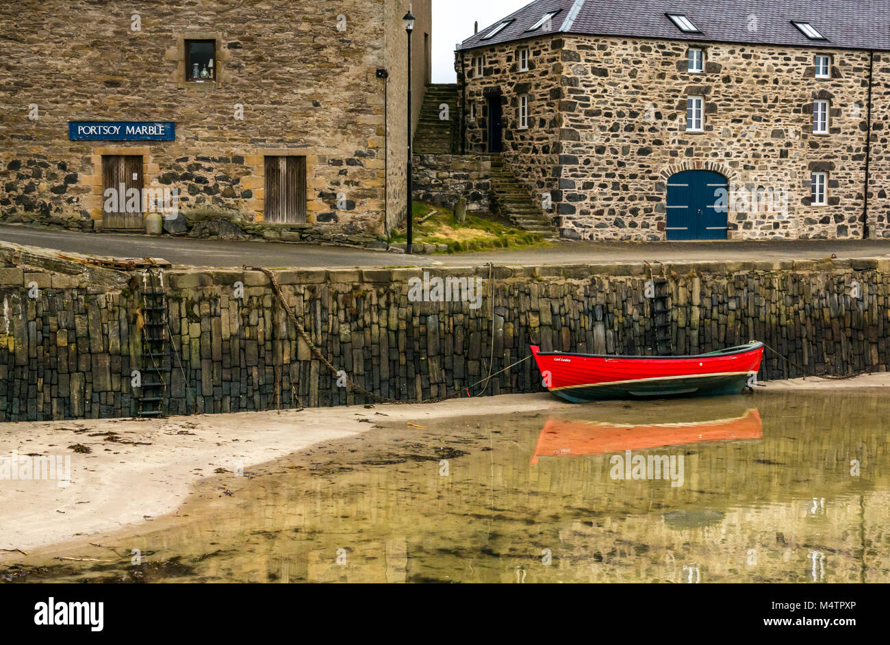 Kleine rote Boot bei Ebbe, malerischen Hafen, Portsoy, Aberdeenshire, Schottland, Großbritannien, mit Wasser Reflexionen und historischen Gebäuden Stockfoto
