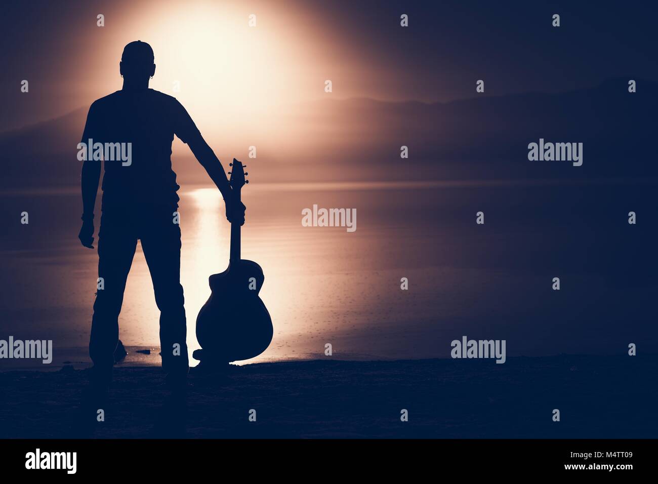Gitarrist mit akustischer Gitarre Sonnenuntergang Silhouette Konzept Foto mit der rechten Seite kopieren. Stockfoto