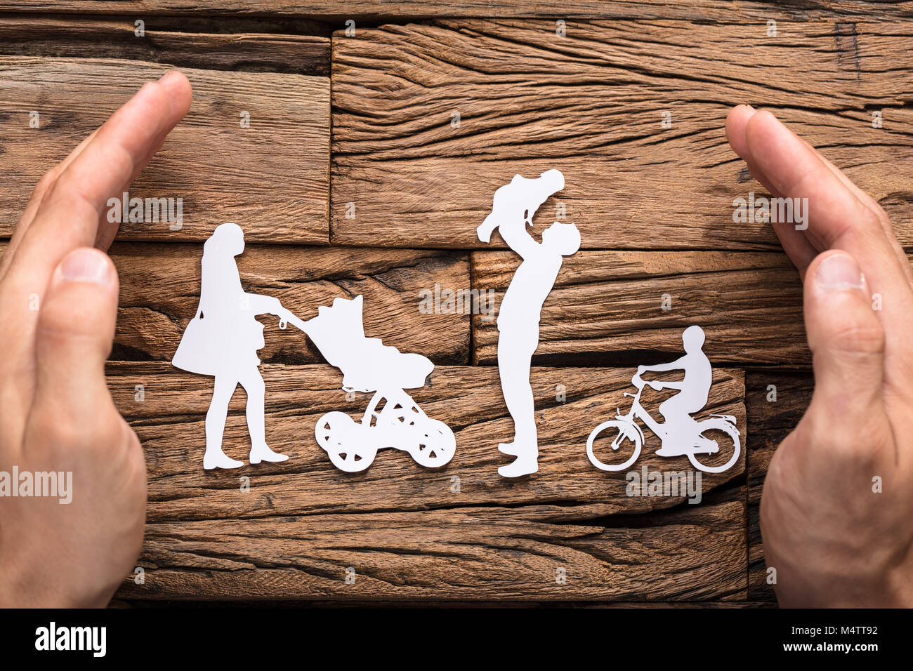 Nahaufnahmen der Hände zum Schutz der Familie weiss Papier schneiden Sie auf hölzernen Tisch Stockfoto