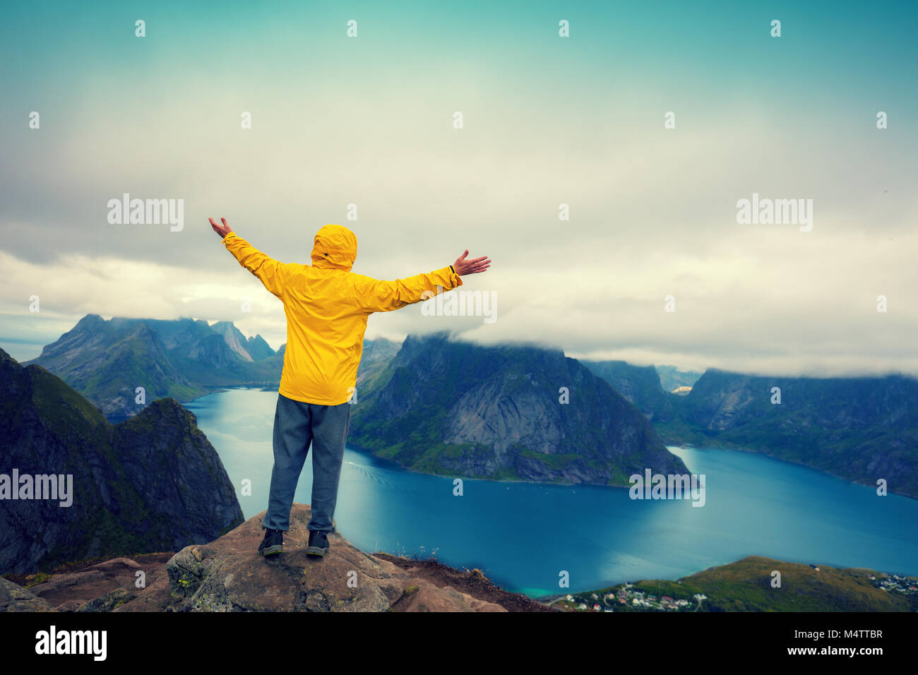 Panorama Blick auf den Fjord vom Berg. Mann mit den Händen in der Luft stehend auf einer Klippe von Reinebringen montieren. Schönen Berg landscap Stockfoto