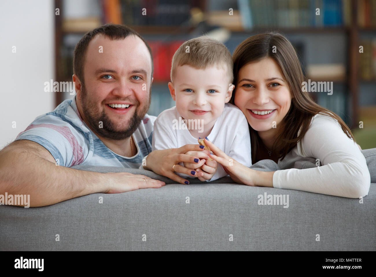 Fotos von lächelnden Familie mit Sohn sitzen auf graue Sofa Stockfoto