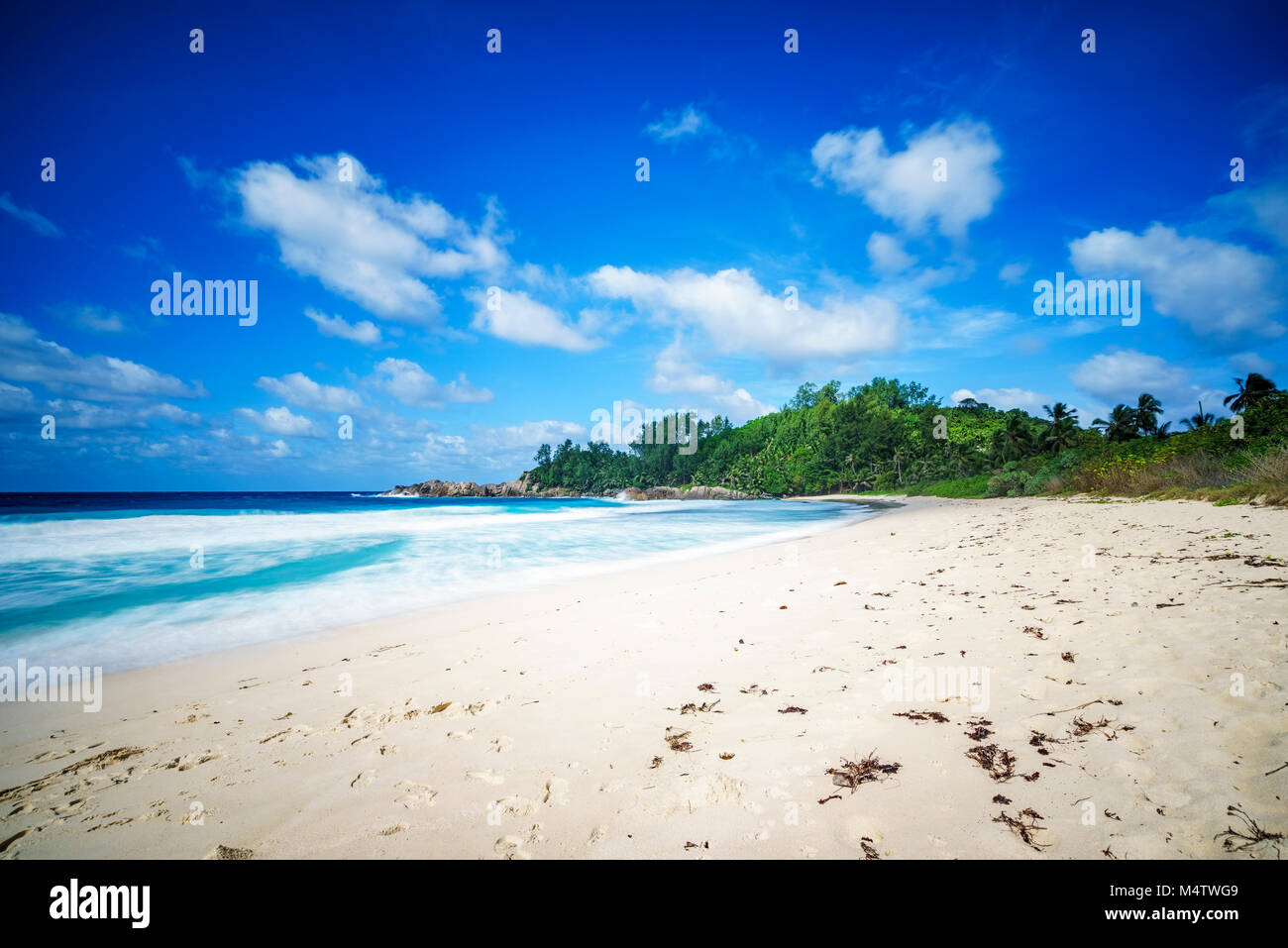 Schönes Paradies Tropischer Strand mit Palmen, Granitfelsen, weißer Sand, blauer Himmel und türkisfarbenem Wasser, Polizei Bay, Mahé, Seychellen Stockfoto
