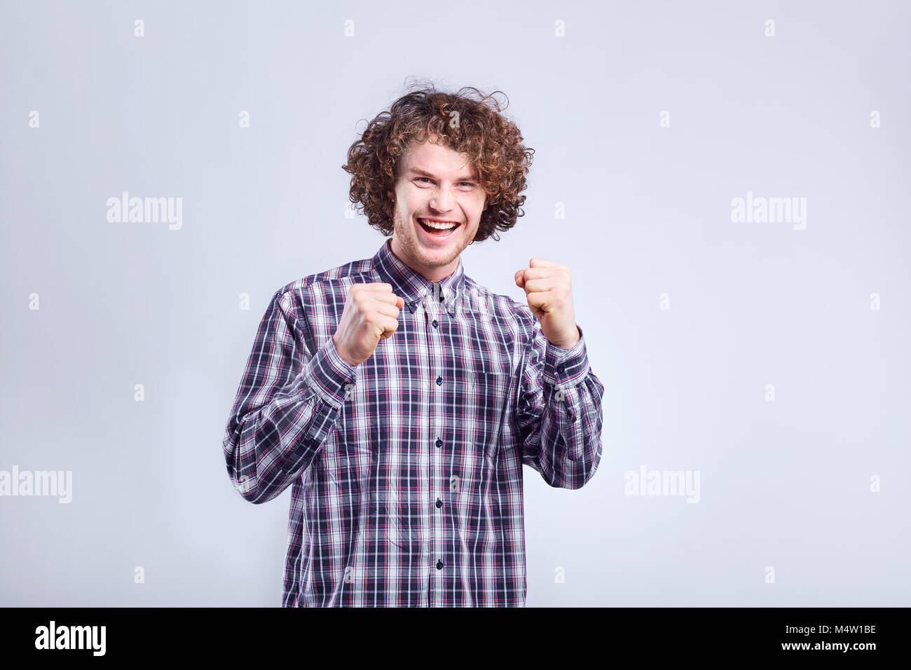 Curly junge Mann überrascht, freudige Emotion auf seinem Gesicht. Stockfoto