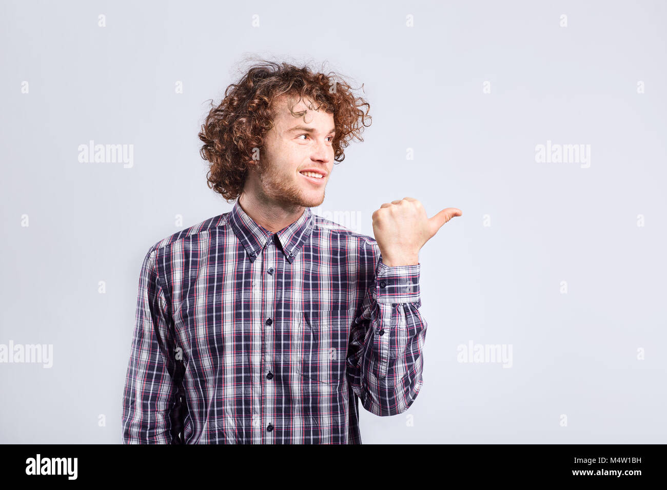 Curly Kerl mit positiven Emotionen auf seinem Gesicht Punkte mit seinem fing Stockfoto