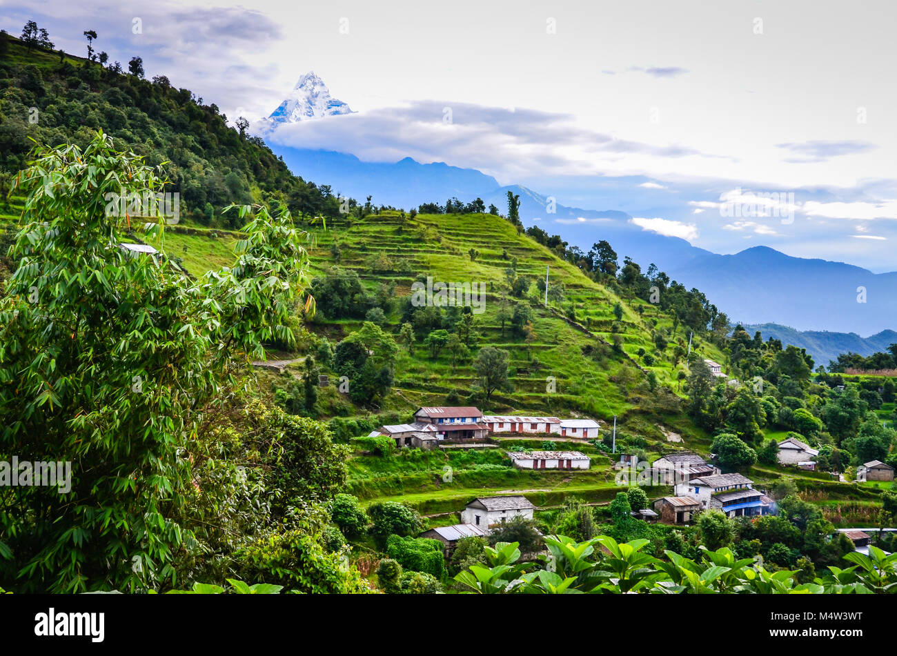 Ländliche Dorf auf terrassierten Hang entlang der Annapurna Trail in die Berge des Himalaja in Nepal mit schneebedeckten Berg Tipp im Hintergrund. Stockfoto