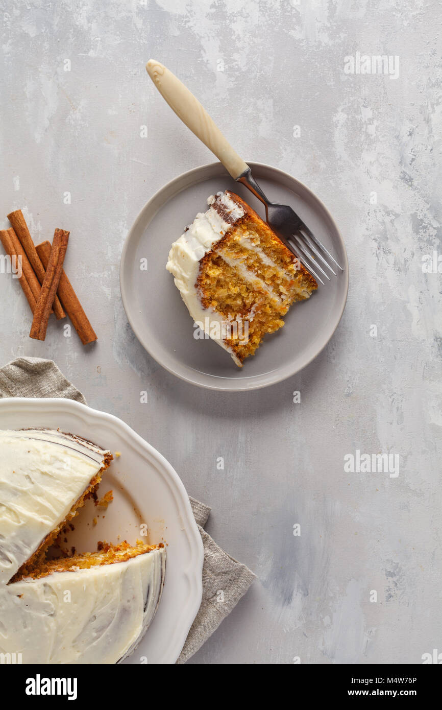 Stück Karotte hausgemachte Kuchen mit Weiß Creme auf grauem Hintergrund. Festliches dessert Konzept. Stockfoto