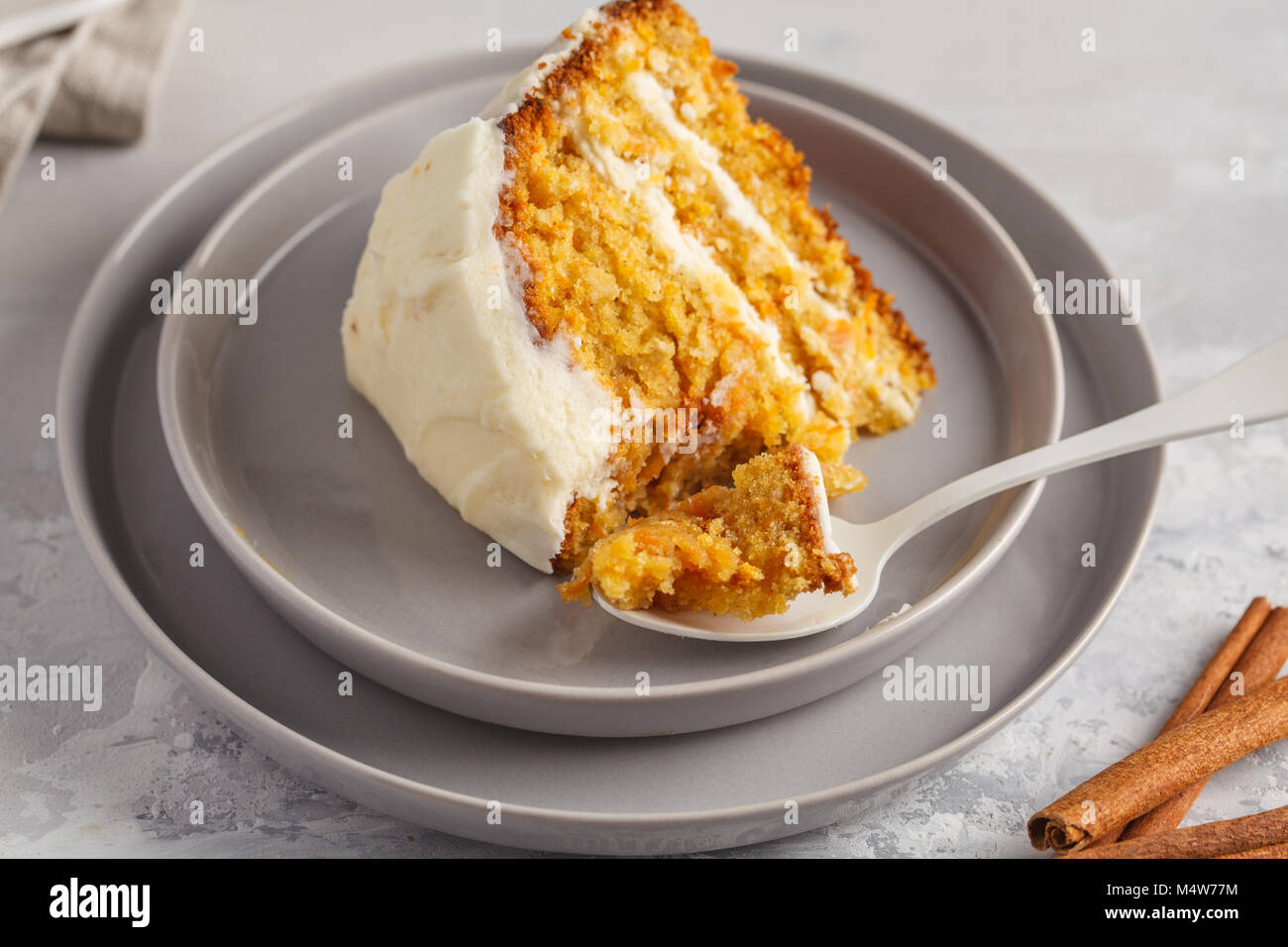 Stück Karotte hausgemachte Kuchen mit Weiß Creme auf grauem Hintergrund. Festliches dessert Konzept. Stockfoto