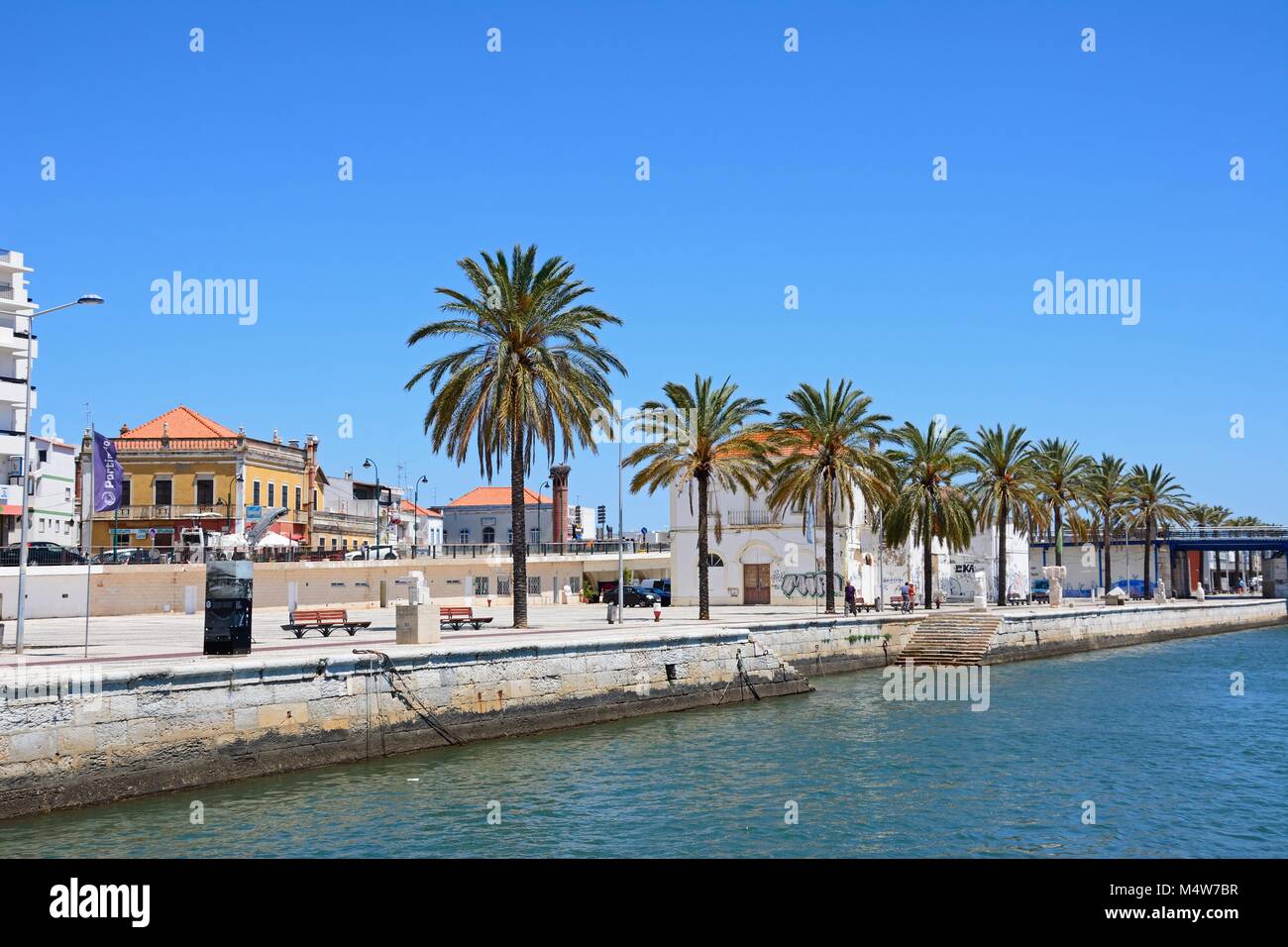 Palmen gesäumten Promenade neben dem Fluss Arade mit städtischen Gebäude auf der Rückseite, Portimao, Algarve, Portugal, Europa. Stockfoto