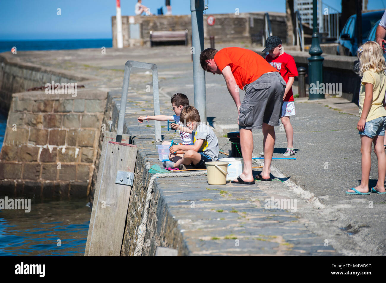 Kinder auf der Hafenmauer in Aberaeron West Wales an einem sonnigen Sommertag Krabben Stockfoto