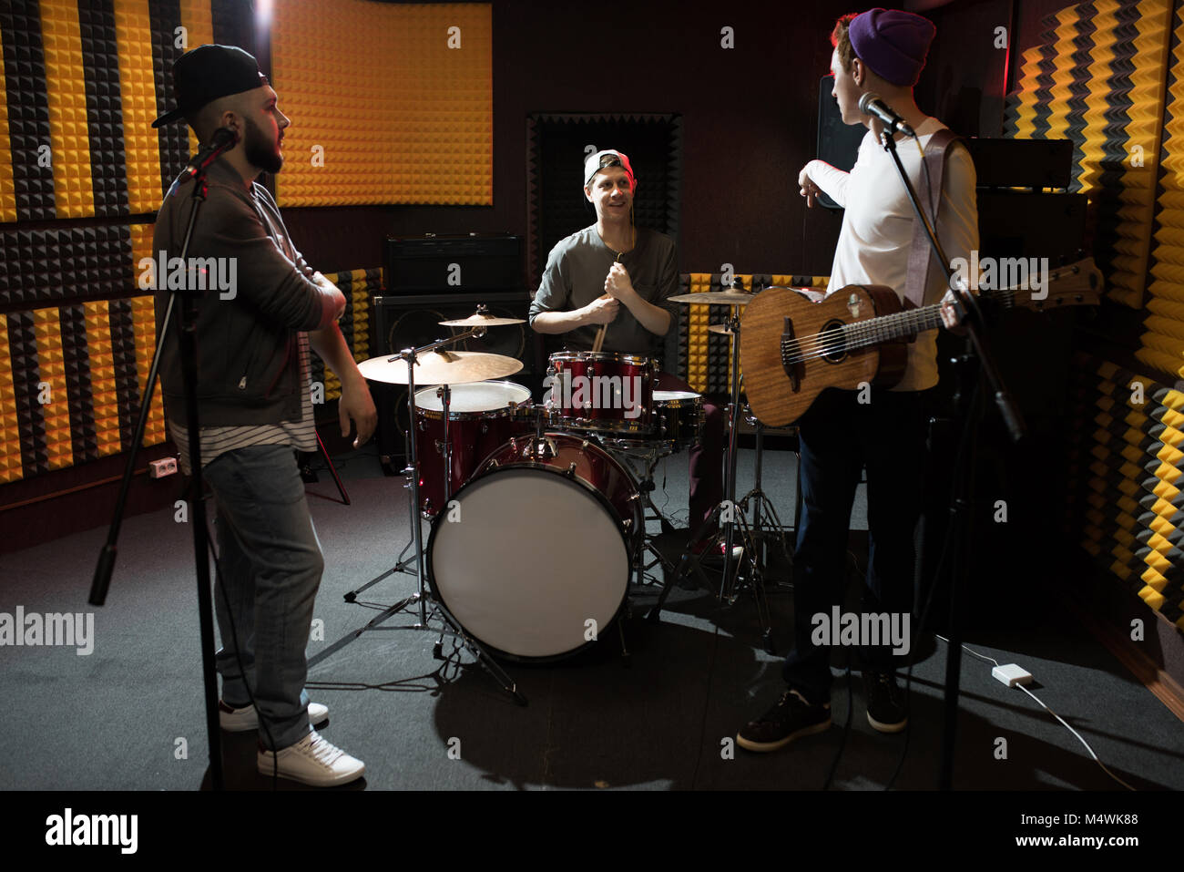 Band junger Musiker Diskussion haben, während Sie im dim Recording Studio das neue Album Stockfoto
