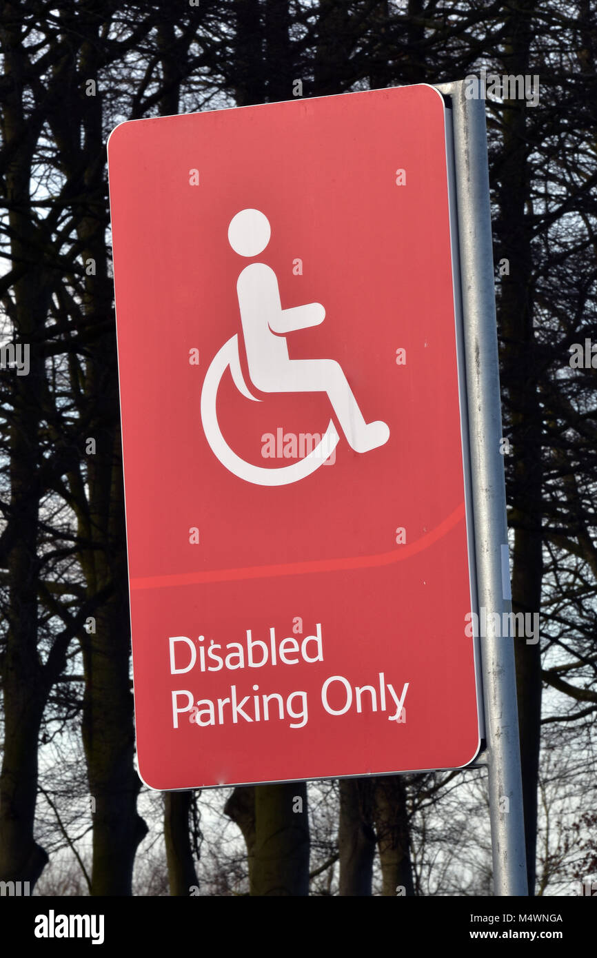 Eine rote und sehr auffällig auffällig Behindertenparkplätze nur Zeichen in einem großen Supermarkt oder SB-Warenhaus Parkplatz. Räume für Parkplatz ein Auto oder Fahrzeug Stockfoto