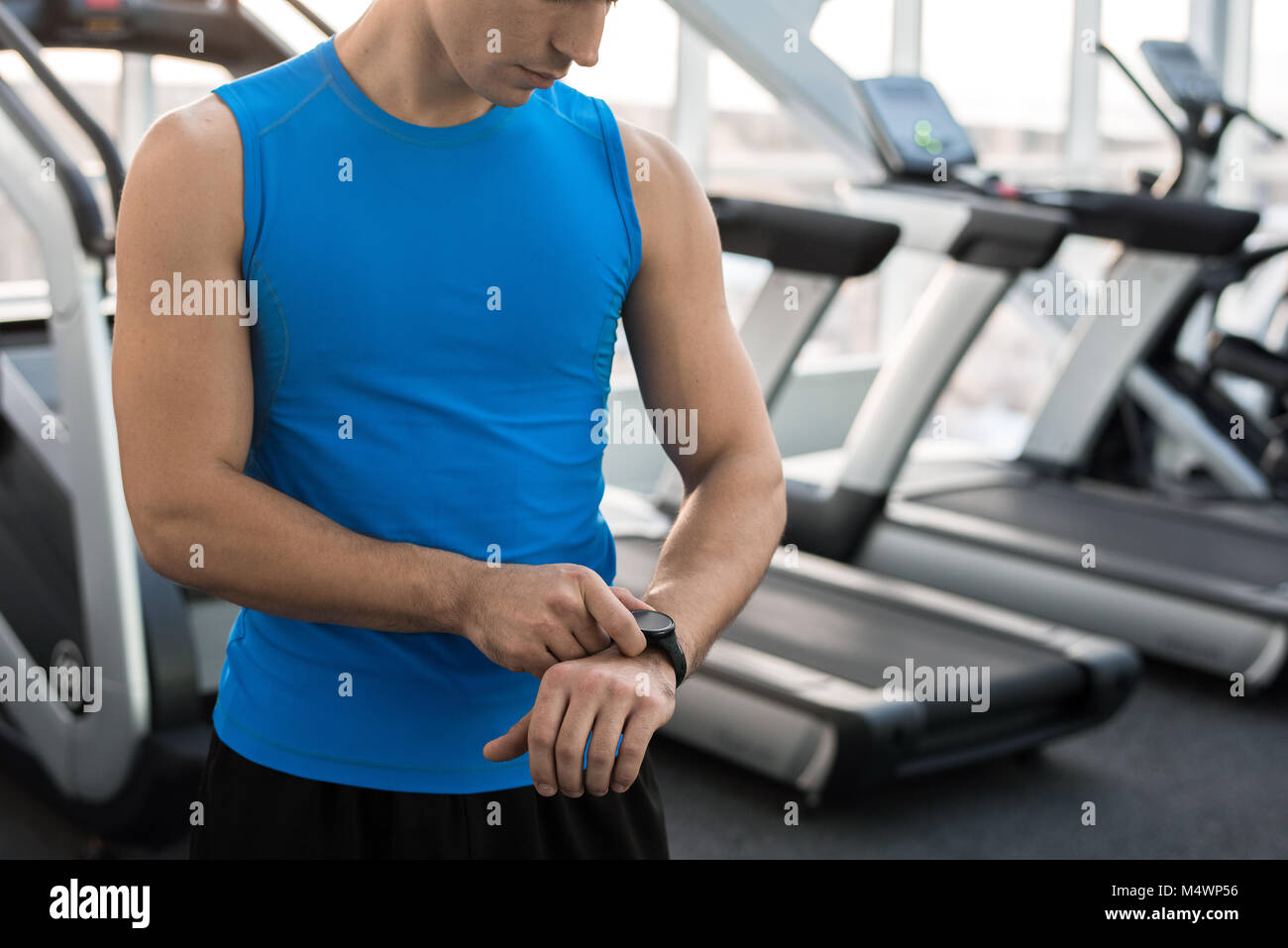Den mittleren Abschnitt Portrait von unkenntlich muskulösen Mann Kontrolle fitness Tracker nach dem Training im Fitnessraum, Kopie Raum Stockfoto