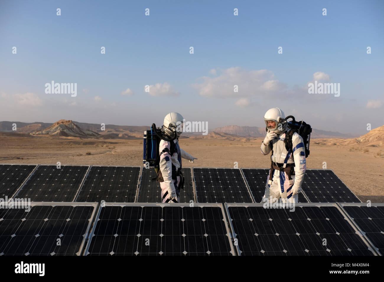 Analoge Astronauten, verkleidet in einem speziellen Raumanzügen, umherwandern das Gelände der Mars-ähnlichen Forschungseinrichtung für den D-MARS (Desert Mars Analog Ramon Station), eine einzigartige Initiative für einen Lebensraum für Planetenforschung, der in einem isolierten Wüstengebiet im Ramon Crater in der Negev-Wüste gebaut wurde. Die Analogastronauten leben in der Forschungseinrichtung und können den Lebensraum nur in Raumanzügen verlassen. Während der Isolation führt das Team eine Reihe von wissenschaftlichen und technologischen Experimenten durch, in der Hoffnung, die Grundlagen für zukünftige bemannte Missionen zum Mars zu schaffen. Stockfoto