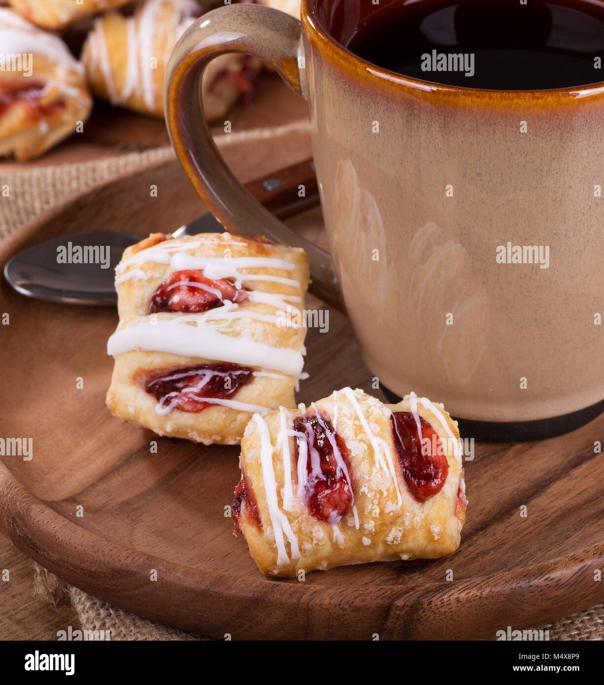 Nahaufnahme der Erdbeere Gebäck auf einer Holzplatte mit einer Tasse Kaffee Stockfoto