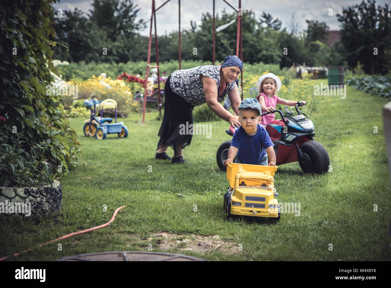 Kinder spielen mit Active Senior Großmutter draußen in der Landschaft als Symbol für glückliche Kindheit Stockfoto