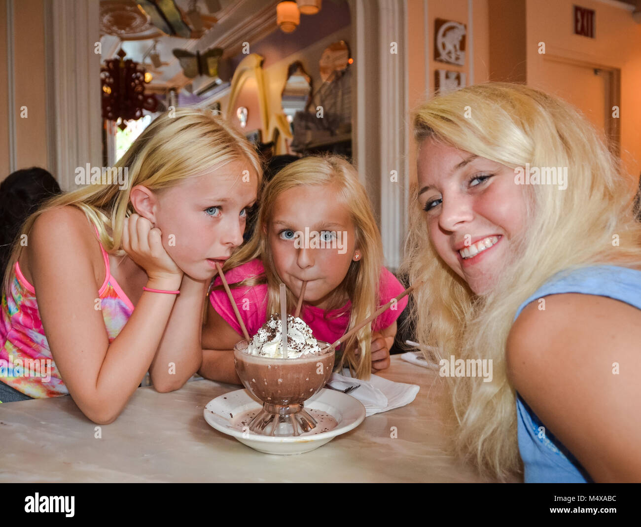 Horizontales Bild von drei Blonden und blauäugigen Mädchen trinken einen gefrorenen Heiße Schokolade Dessert. Stockfoto