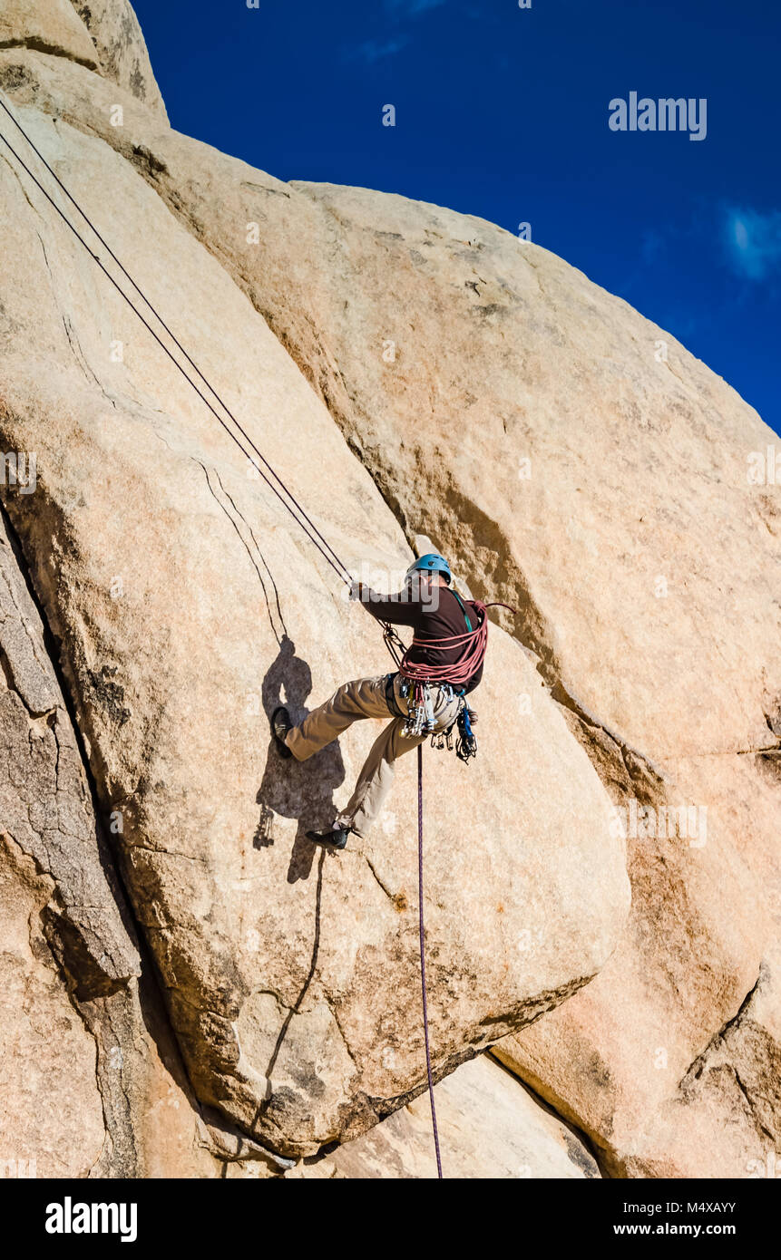 Ein Mann rappels ein Klettersteig am Schnittpunkt Rock, einer 150 Fuß hohe Monzonite monolith als der Geburtsort von Klettern in Joshua Tree Na erkannt Stockfoto
