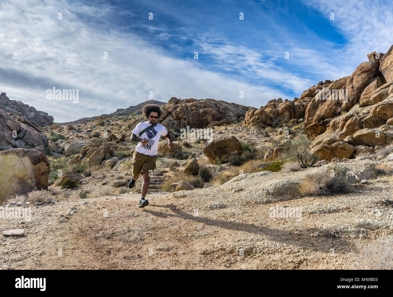 Afrikaner - Mann, Wilde afro Haar fließt, läuft bergab auf Fortynine trail Palms Oase in Joshua Tree National Park. Stockfoto