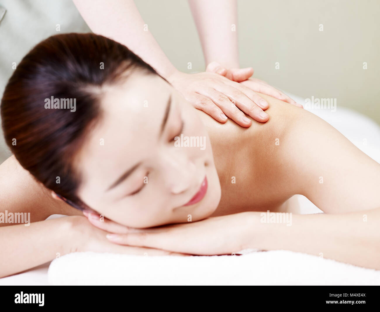 Schöne junge asiatische Frau liegend auf der Vorderseite auf dem Bett empfangen Öl Massage im Spa Salon, auf die Hände der Masseurin konzentrieren. Stockfoto