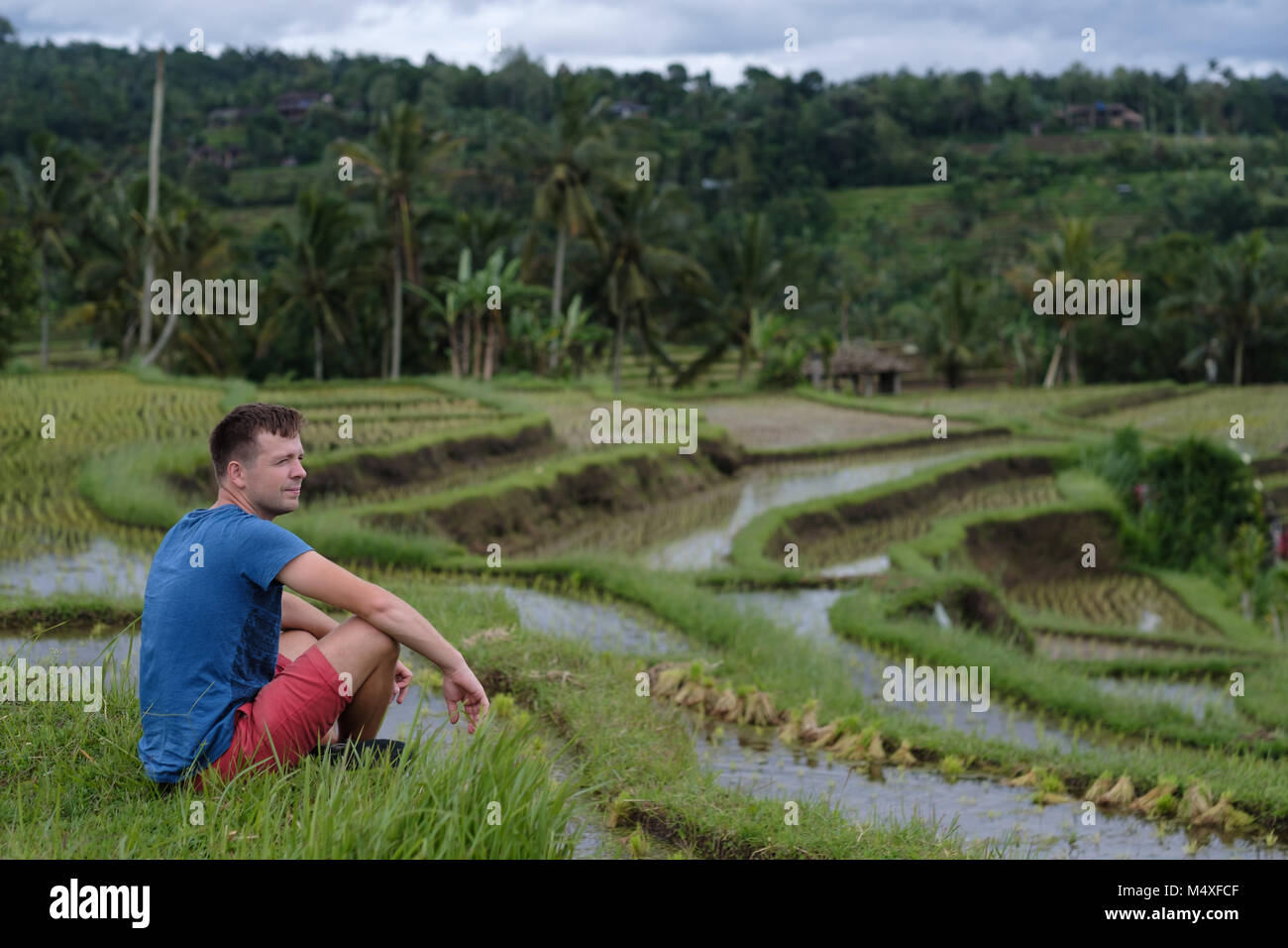 Junger Mann Reisender Sitzen und Entspannen im Freien am Reis Felder auf Bali Indonesien angebaut. Stockfoto