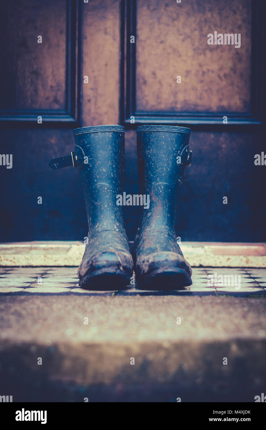 Nahaufnahme von schmutzigen Gummistiefel außerhalb einer Vordertür in Schottland, Großbritannien Stockfoto