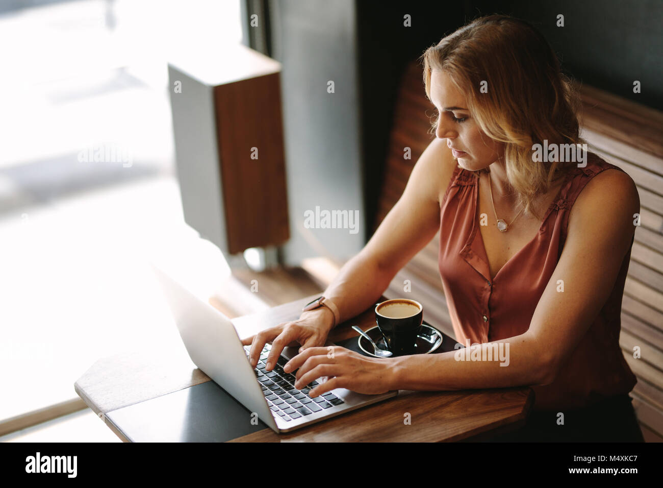 Freelancer an einem Tisch sitzen, Arbeiten am Laptop mit einer Tasse Kaffee auf dem Tisch. Frau tun ihre Arbeit in einem Café sitzen. Stockfoto