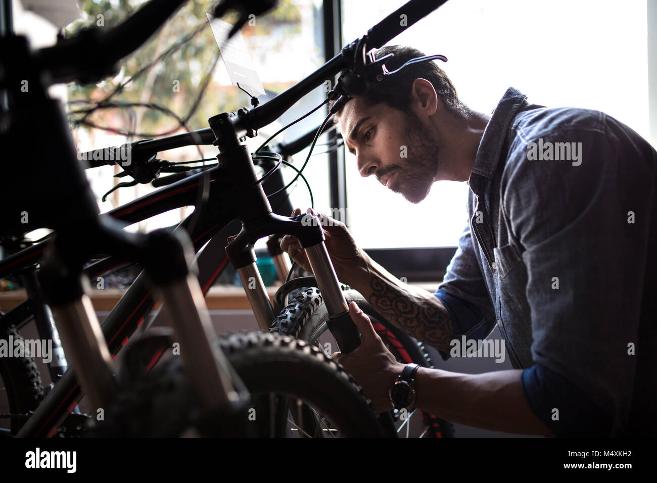 Mechanische Inspektion ein Fahrrad Stoßdämpfer in einem Showroom. Mann an einem Fahrrad showroom Reparaturen. Stockfoto
