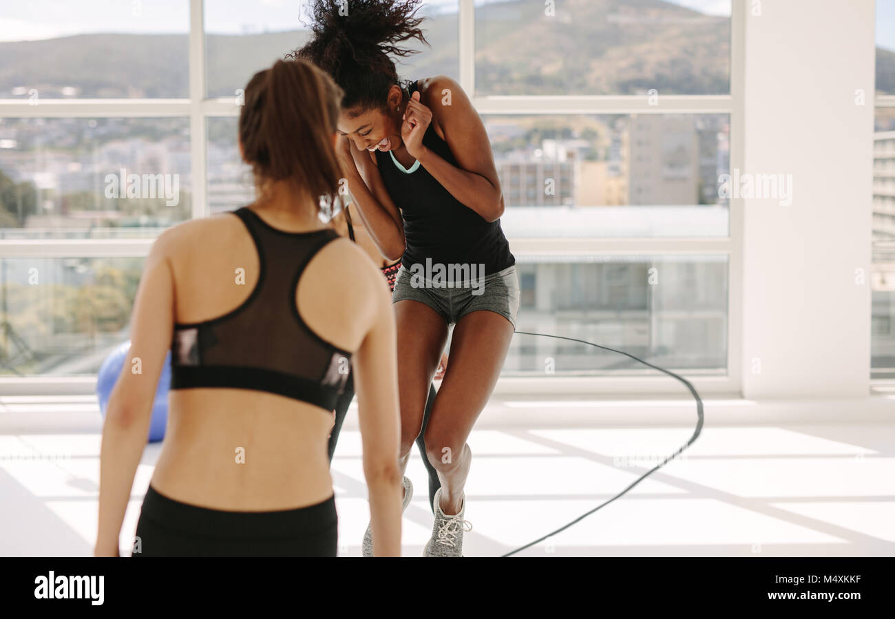 Frau genießen Seilspringen Übung in Fitness Studio mit Freunden. Frauen Spaß beim Training Session im Fitnessstudio. Stockfoto