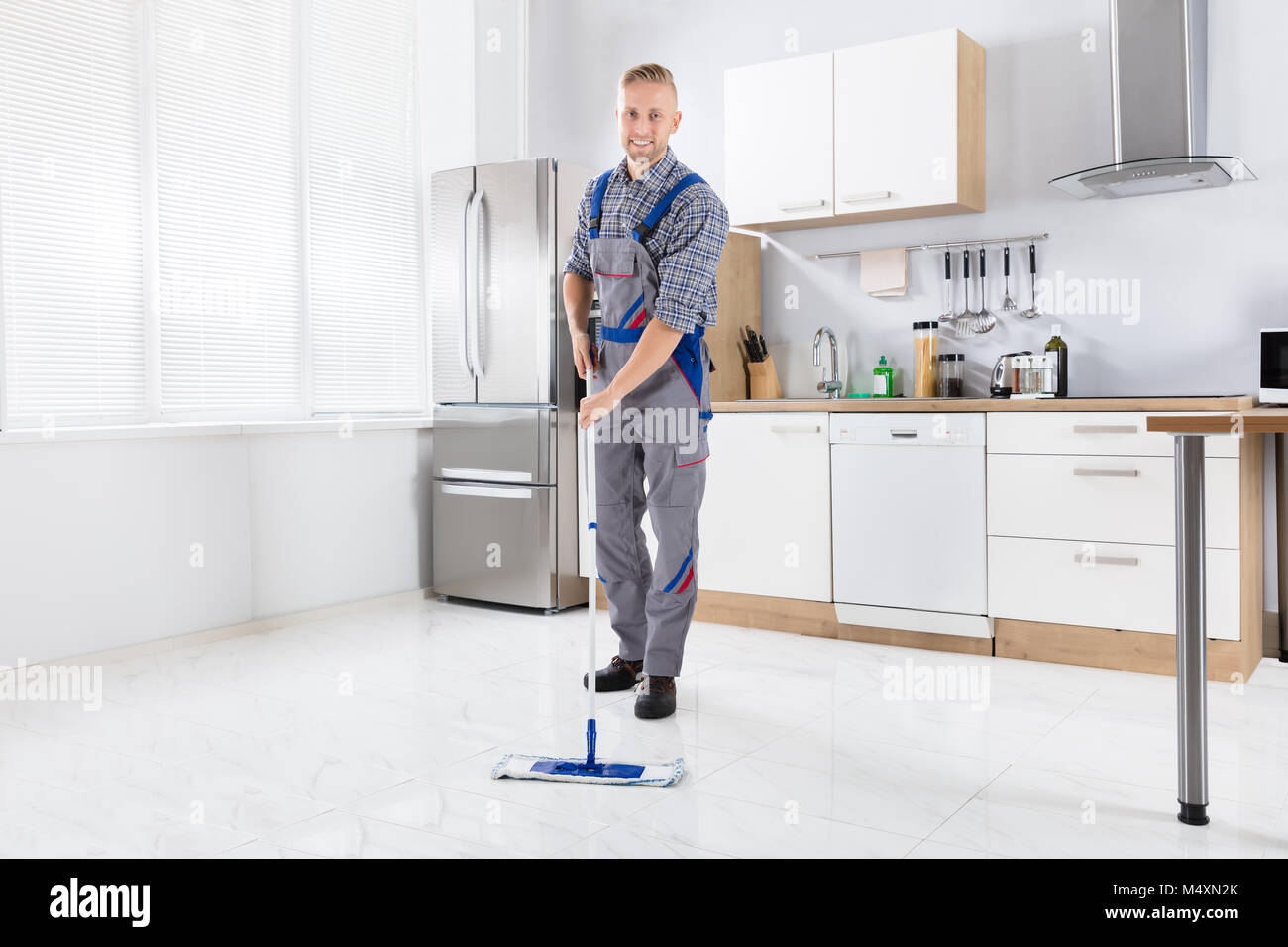 Glückliche junge männliche Arbeiter Wischen, mit Mop In der Küche Stockfoto