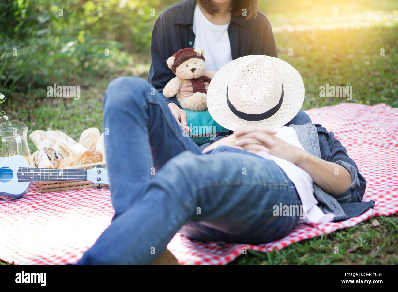 Lässig schöner Mann legte seinen Kopf auf die Knie seiner Frau während Picknick, Outdoor, Korb. Stockfoto