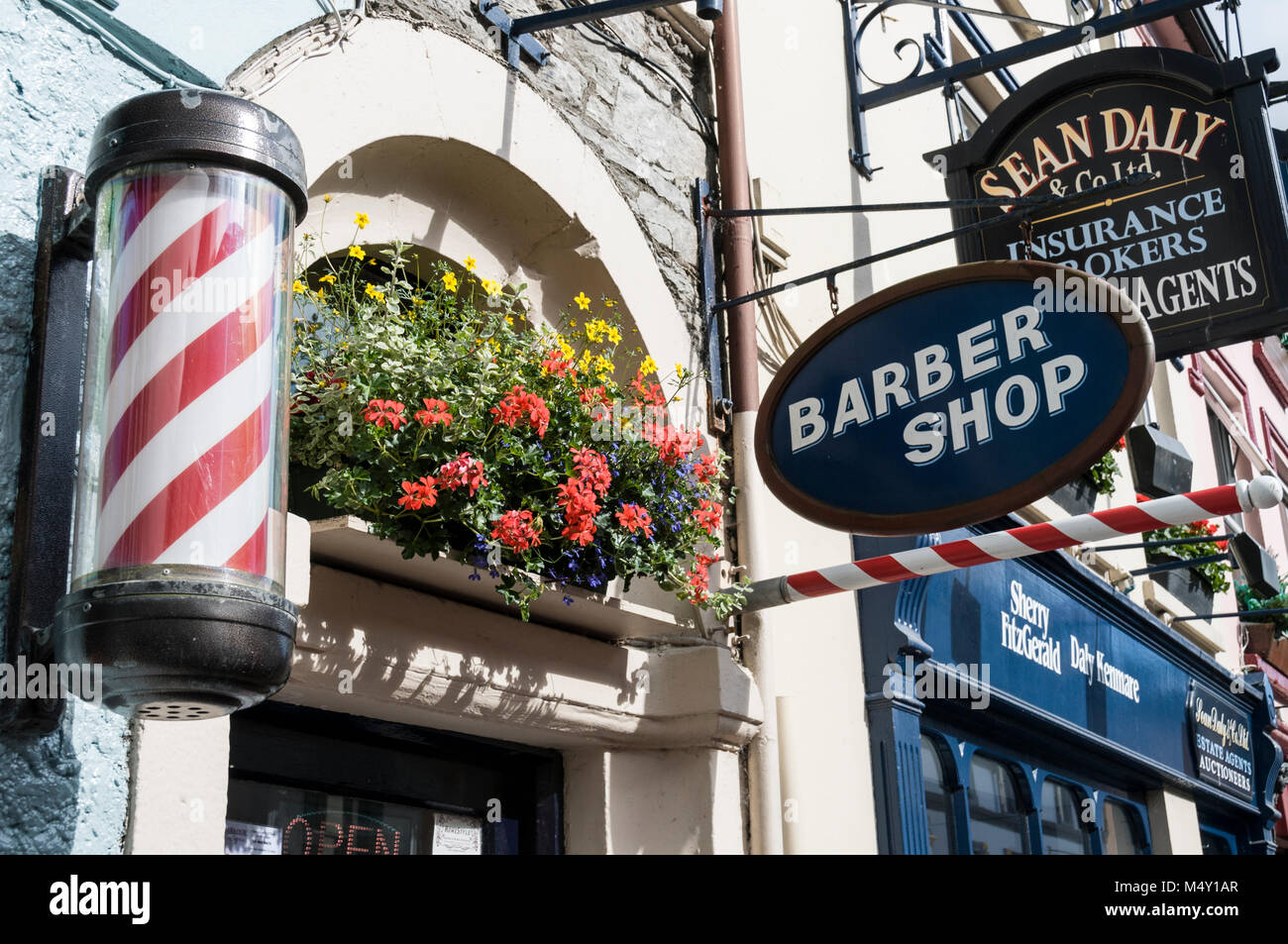 Zahlreiche Schilder vor den Geschäften und Restaurants in der belebten Henry Street in Kenmare in County Kerry, Südirland. Kenmare, eine kleine Touristenstadt, ist das Hauptziel Stockfoto