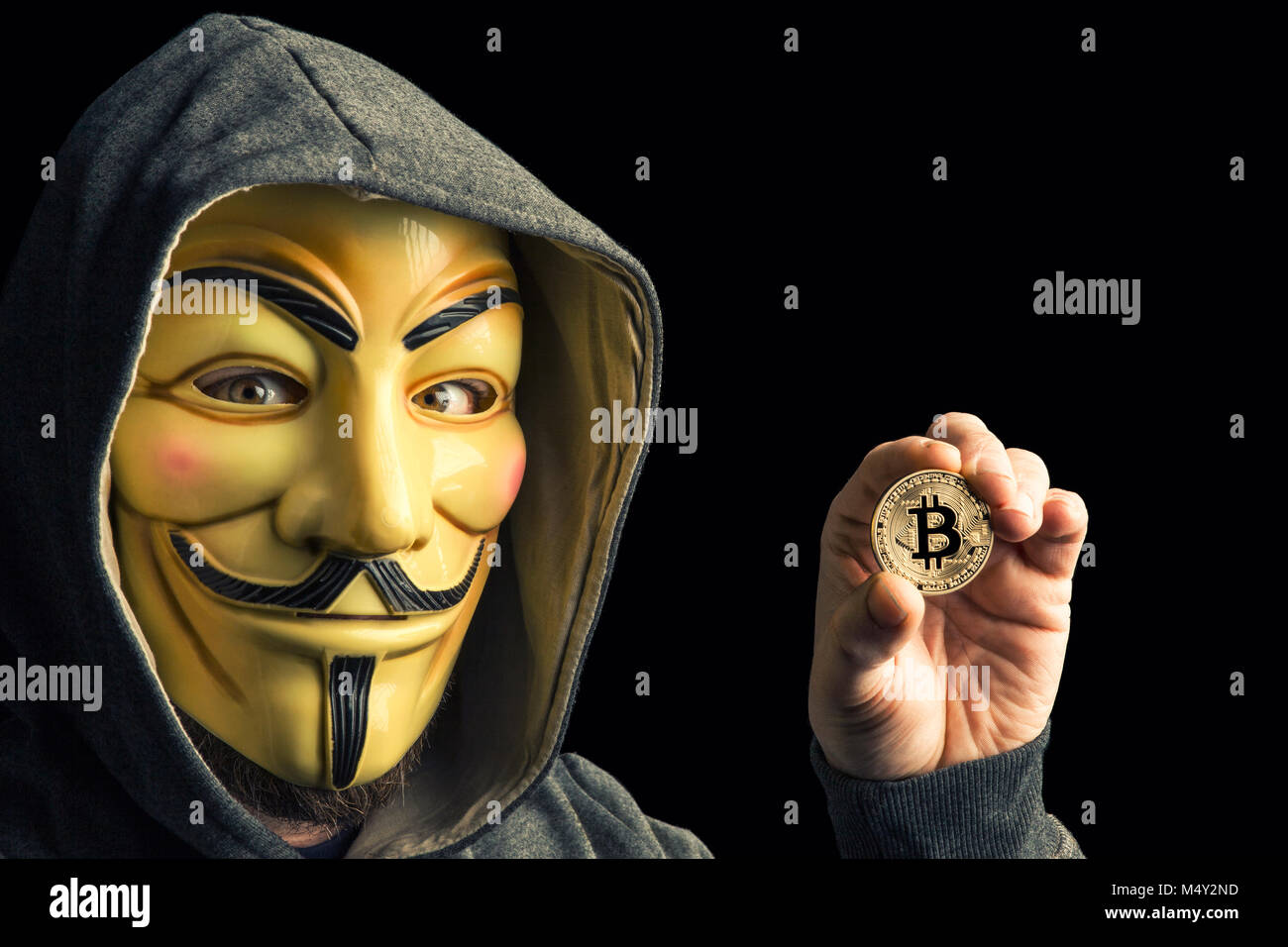 Mailand, Italien, Februar 2018: Hacker halten Golden bitcoin Münze und Verschleiß anonymus Maske. Editorial Foto. Stockfoto