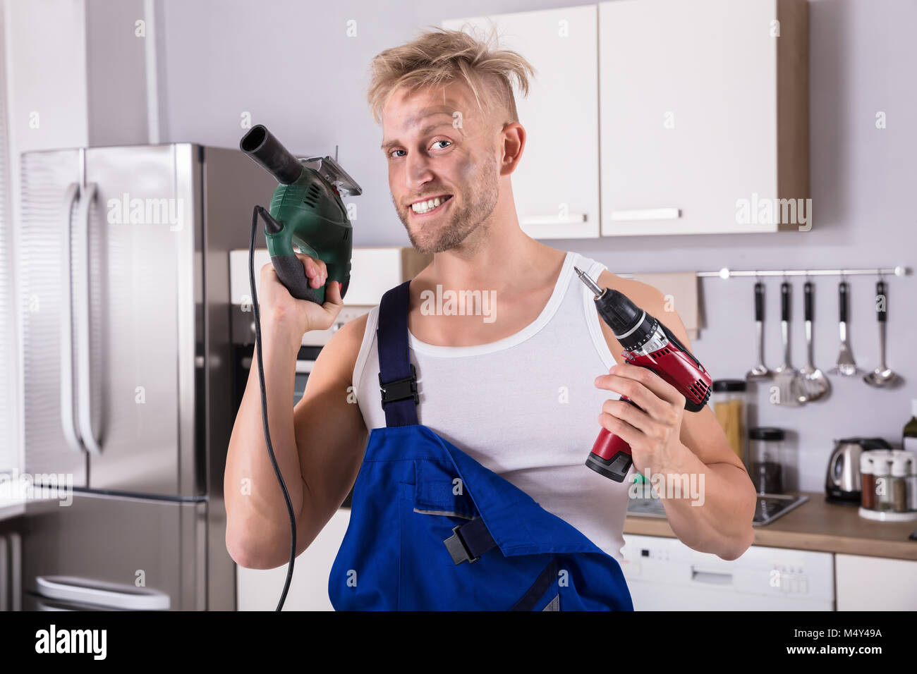 Porträt einer zuversichtlich Techniker Holding elektrische Bohrmaschine und Schraubendreher Stockfoto