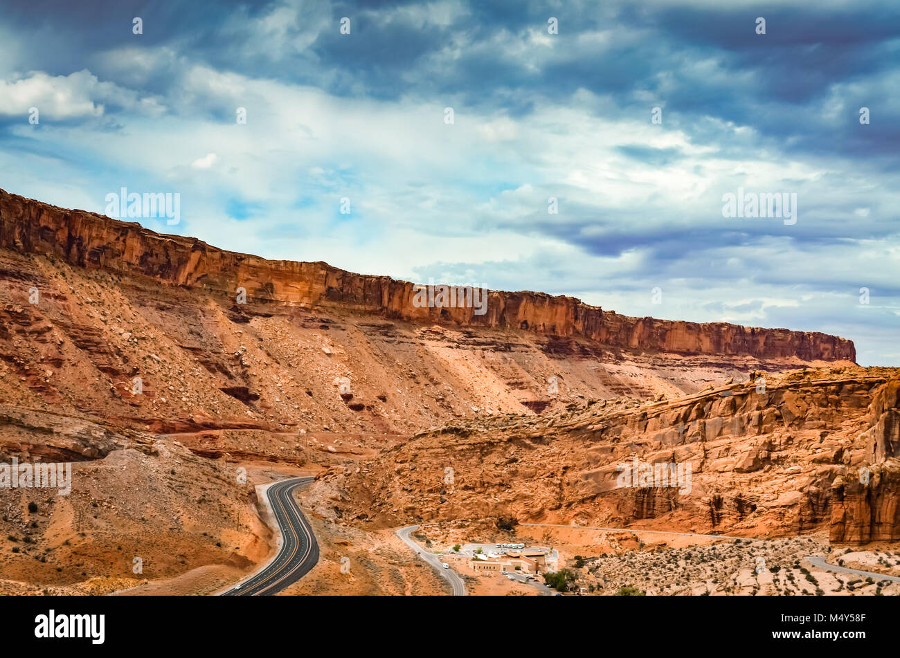 S-förmig gewundenen Straße unter roten Felsformationen an einem bewölkten Tag im Arches National Park. Stockfoto