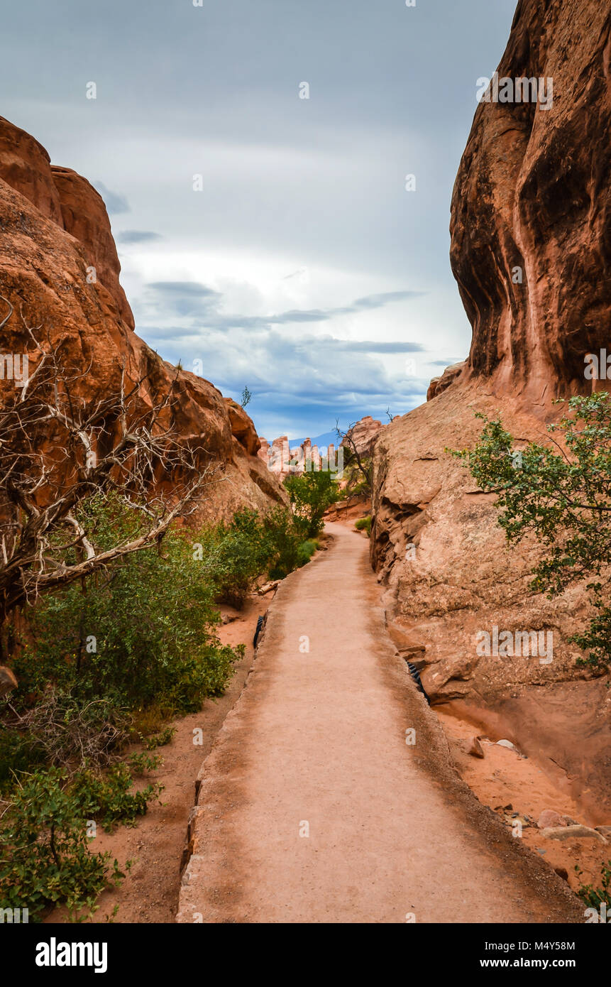 Zugänglichen Pfad, gepflasterte für Rollstuhlfahrer, im Arches National Park. An einem bewölkten Tag, wo Felsformationen umschließen den Weg gesehen, der Anblick ist, einige Stockfoto