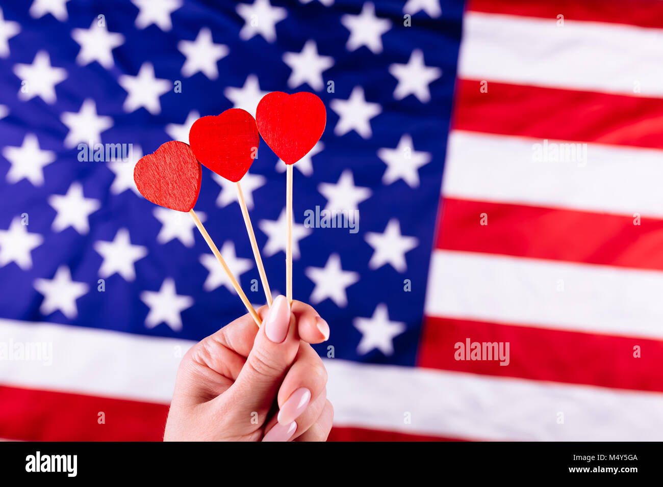 Drei rote Herzen Form auf den Stick vor der amerikanischen Flagge. Visuelles Konzept der Vorbereitung für Tag der Unabhängigkeit. Am 4. Juli patriotischen consept. Stockfoto