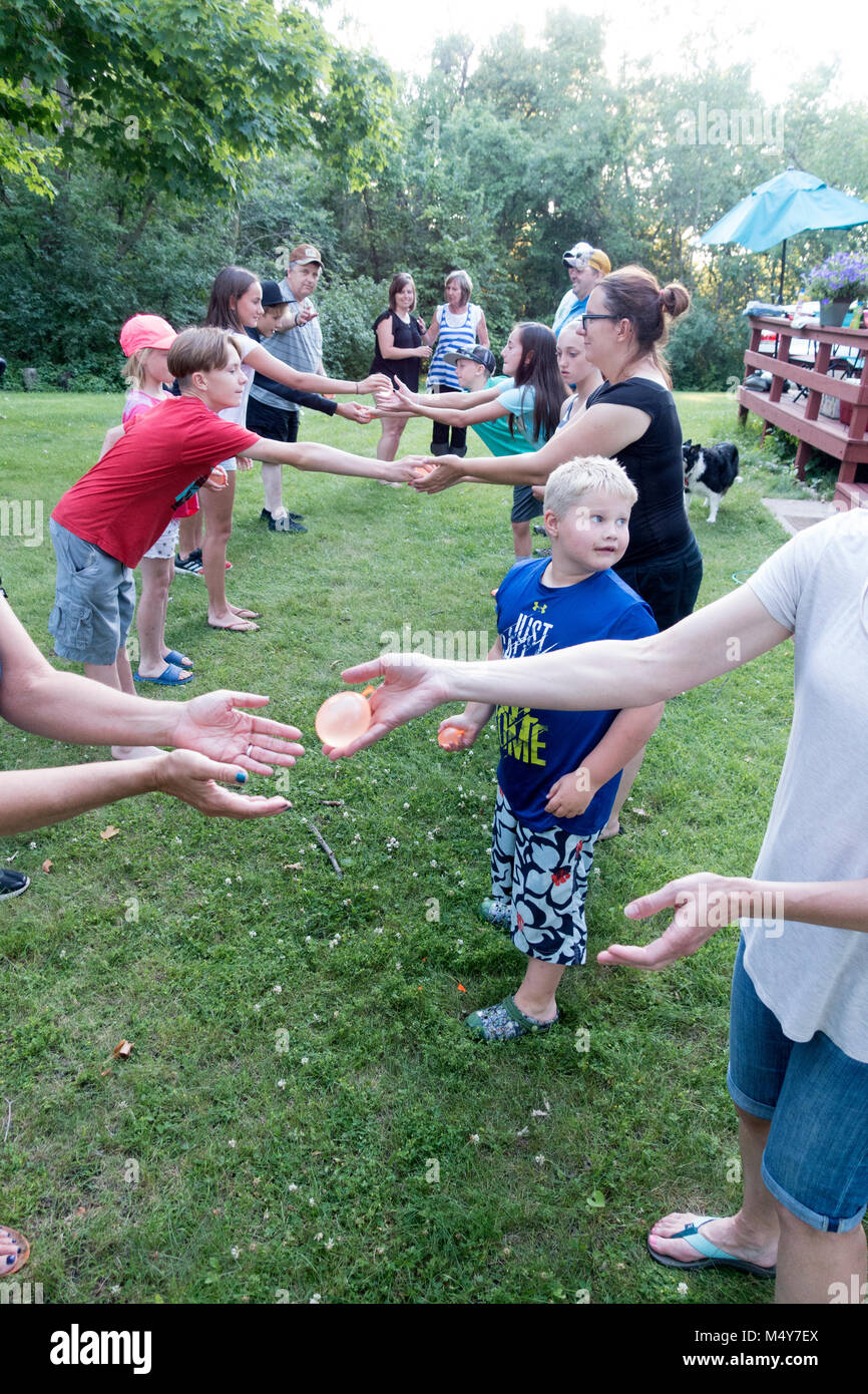 Erweiterte Familie von drei Generationen eine Wasser-ballon Spiel werfen. Clitherall Minnesota MN USA Stockfoto