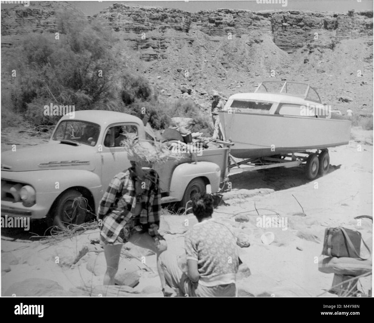 Foto zeigt das Schleppen DER KABINE BOOT AN DEN RAND DES FLUSSES IN DER VORBEREITUNG FÜR DEN START DER MEXICAN HAT EXPEDITION DURCH DEN GRAND CANYON FÜR 1952. Genommen: 12. Juli 1952 unter Lees Ferry. Fotograf STEVE LEDING. CIRCA 1952. Grand Canyon Nat Park historische Fluss Foto. Stockfoto