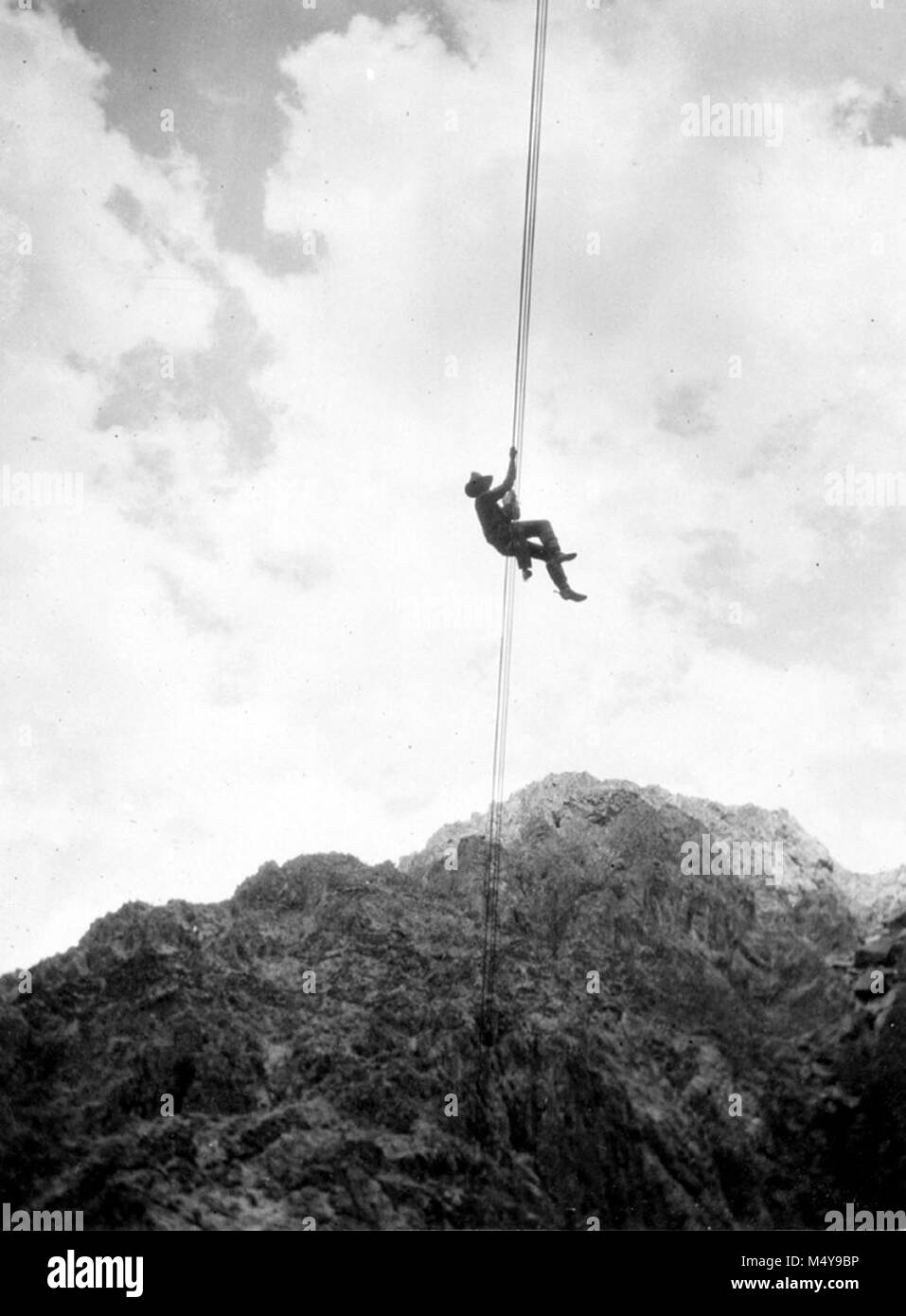 K. HOWARD AUF HALBEM WEG ÜBER DEN ROST Kabel über dem Colorado River in der Nähe von Phantom Ranch. HOWARD IST DER ÜBERQUERUNG DES FLUSSES VON HAND, nicht mit der Seilbahn. Von der William H. CLAFLIN FOTOALBUM (Katalog Nr. 21089 GRCA). Datum: 1914 Grand Canyon Nat Park historische Fluss Foto. Stockfoto