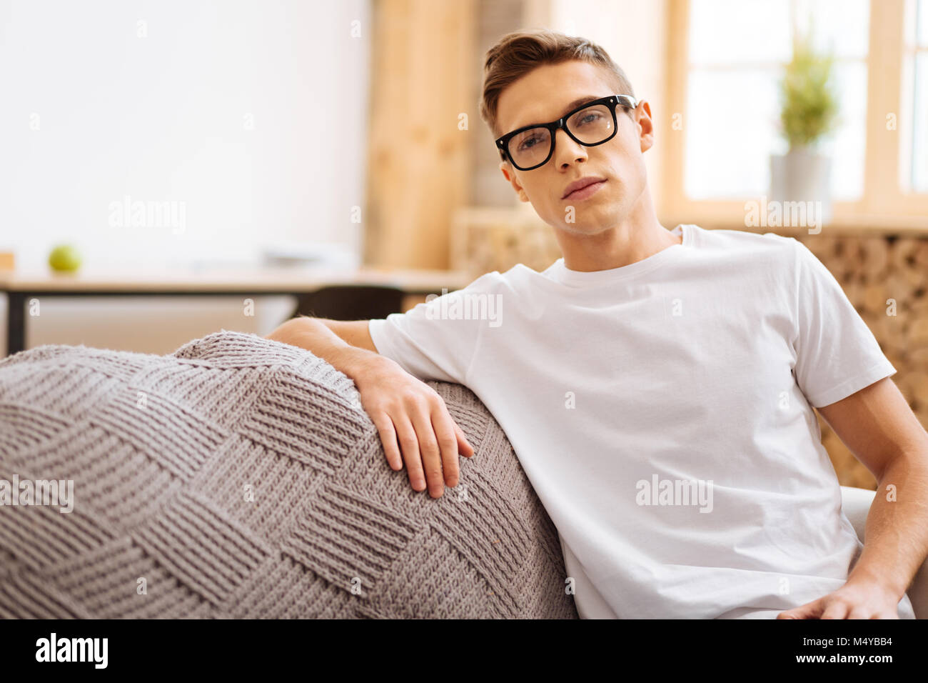 Ernsthafte junge Mann sitzt auf der Soda und Denken Stockfoto