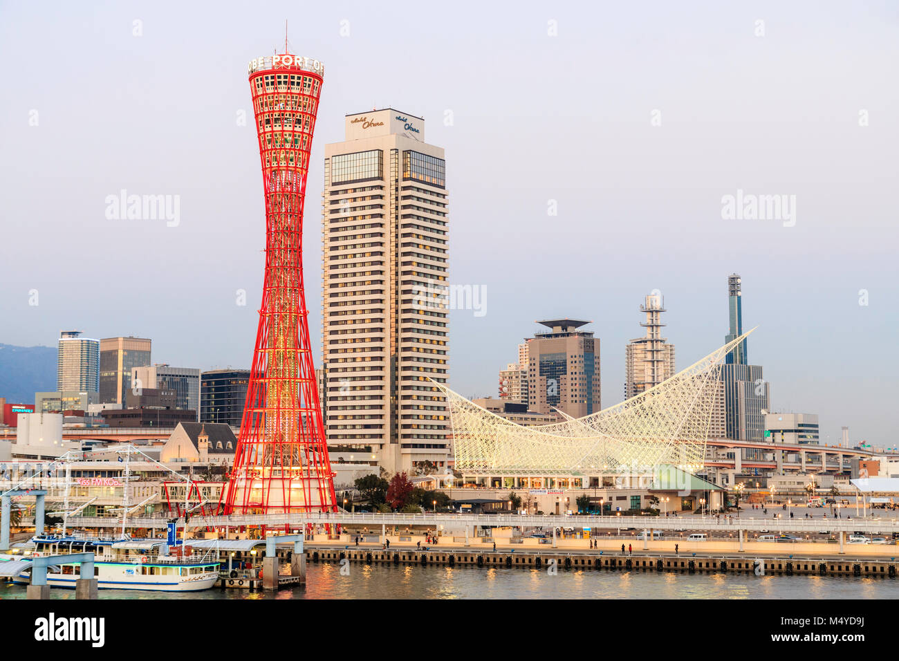 Japan, Kobe. Red Kobe-hafen, mit Okura Hotel hinter, und das Maritime Museum. Twilight nach Sonnenuntergang vor der Nacht. Stockfoto