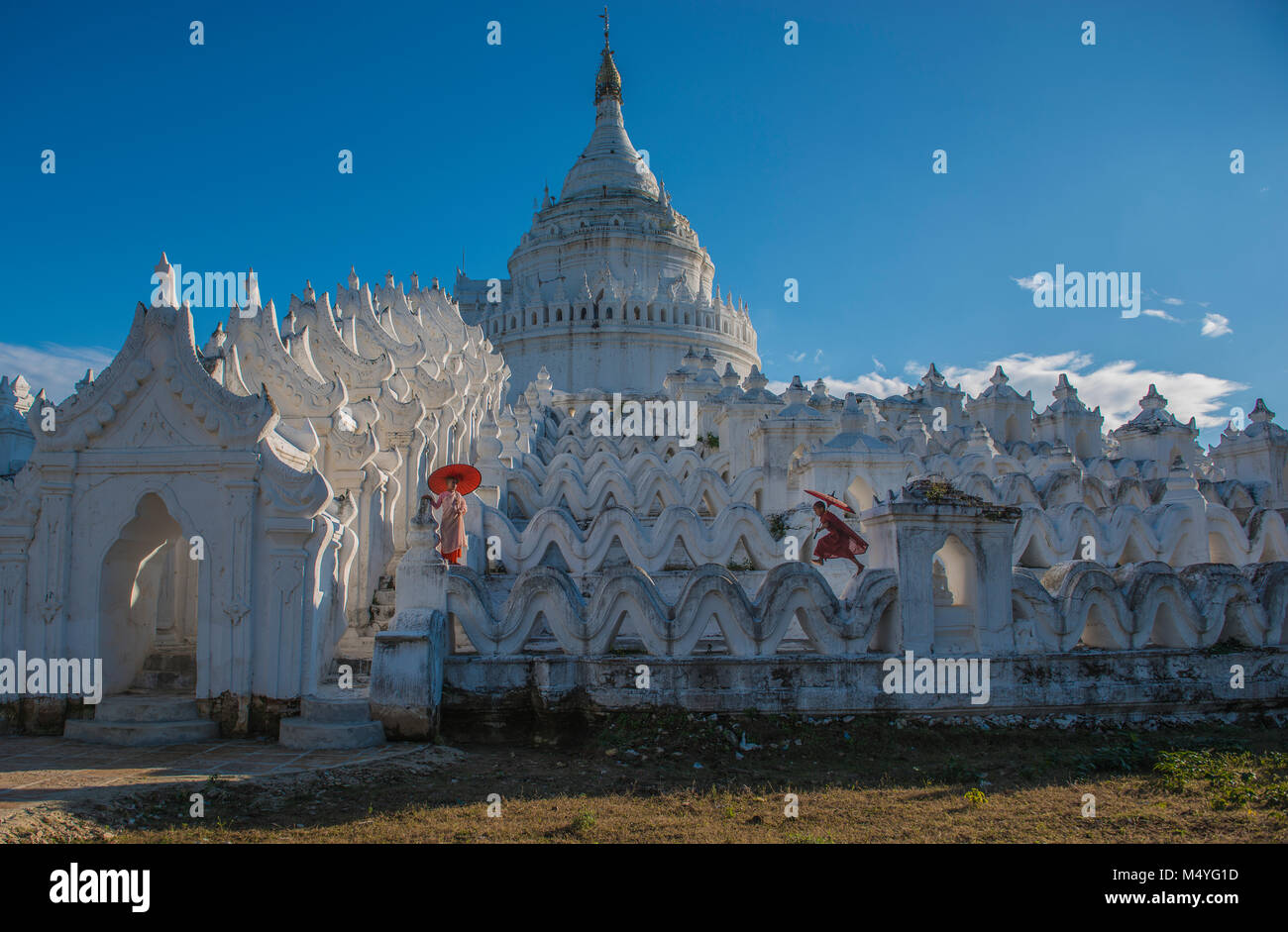 Mönch mit roten traditionellen Kostümen und rotem Schirm in buddhistischen riesigen Tempel Stockfoto