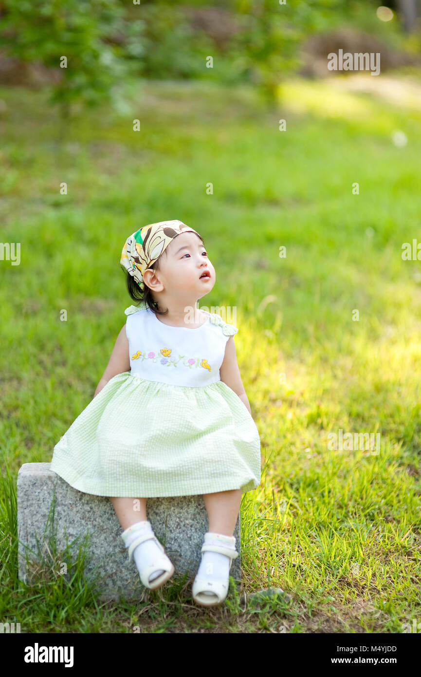 Little Baby sitzen auf der Wiese beobachten den Himmel Stein Stockfoto