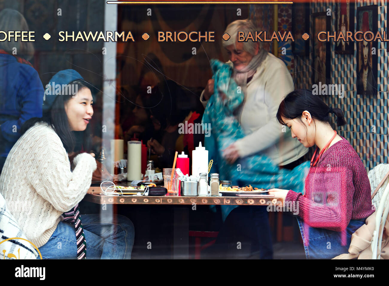 Ehrliches Bild von zwei jungen Frauen chinesischen Ursprungs genießen Sie eine Mahlzeit und ein Chat in einem Cafe, echtes Leben nicht inszeniert. Stockfoto
