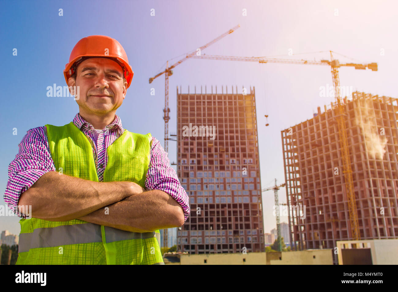 Die Builder in einem Schutzhelm, vor dem Hintergrund von Kränen und ein Gebäude Objekt Stockfoto